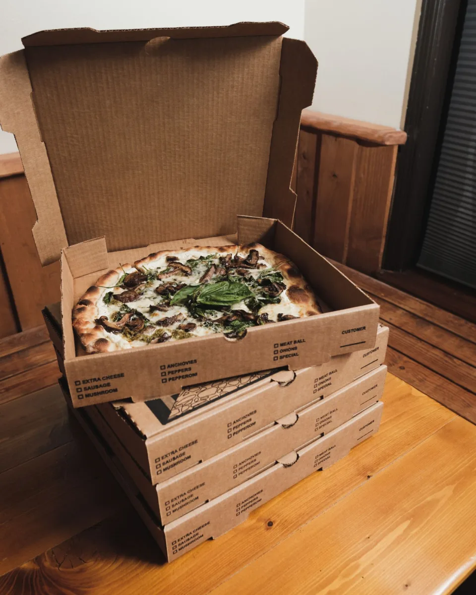 Stack of pizza boxes with an open box on top